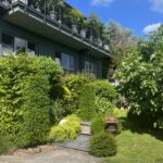 Modernes Haus mit üppigem Garten und Balkonpflanzen