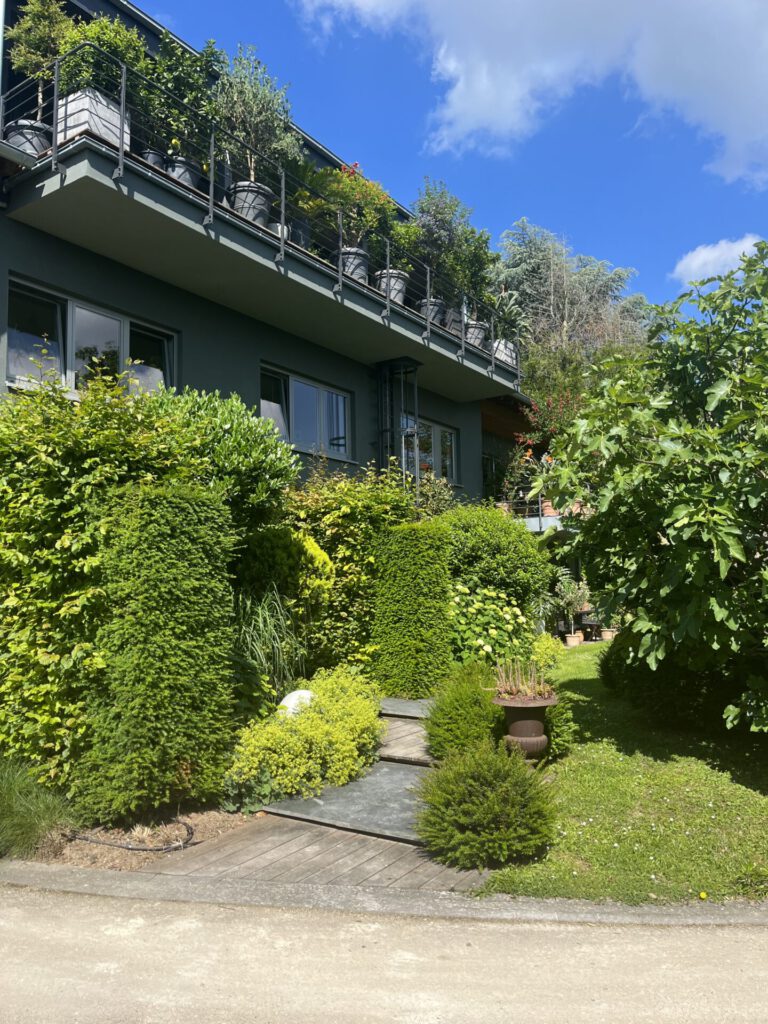 Modernes Haus mit üppigem Garten und Balkonpflanzen