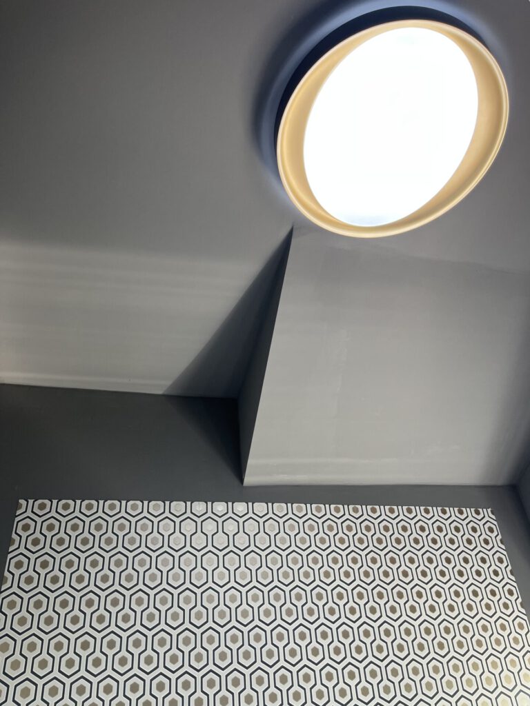 Runde Deckenleuchte über gemusterter Wand mit Fliesen