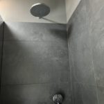 Moderne Regendusche mit grauen Fliesen im Badezimmer